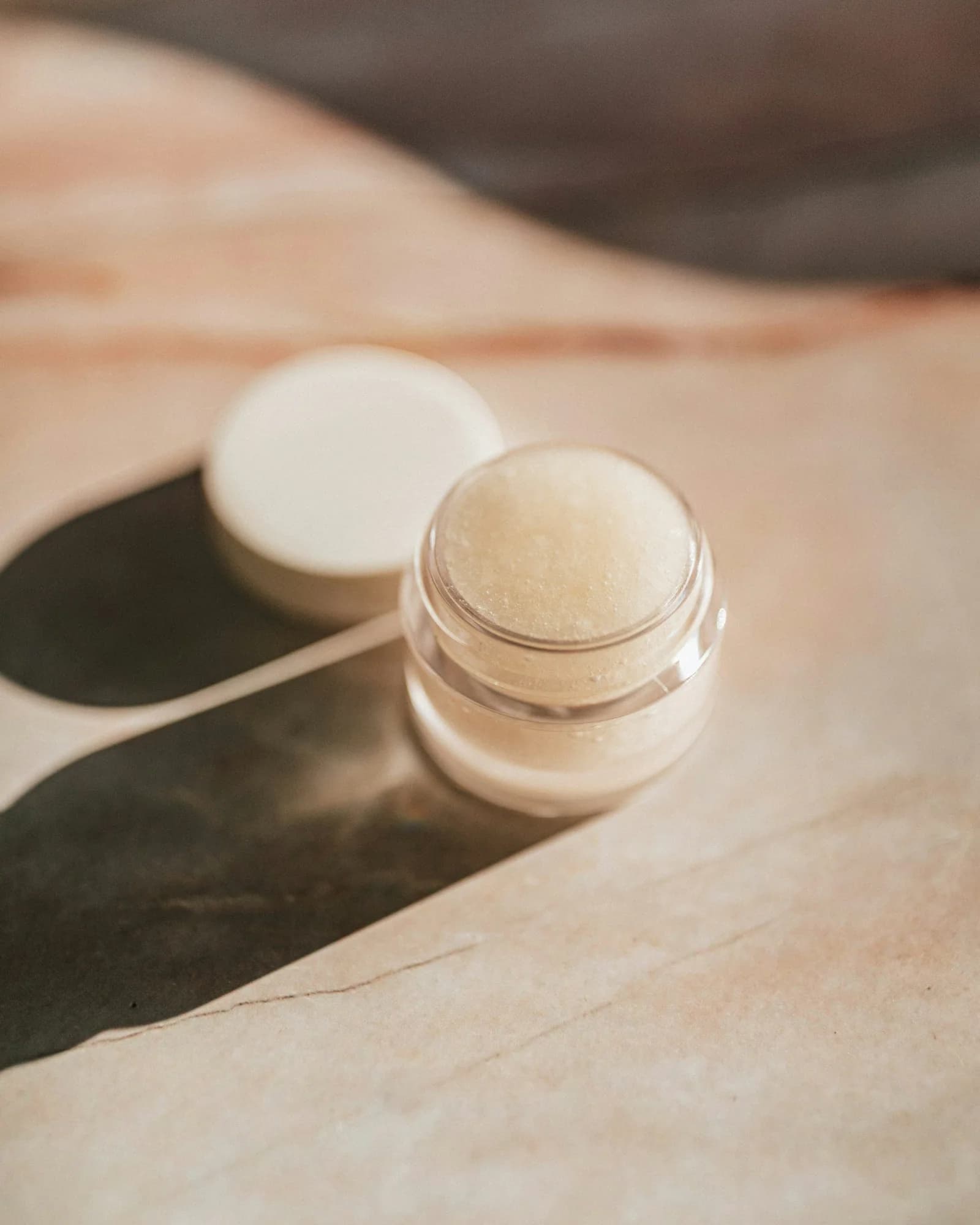 Open jar of rich face cream in soft light