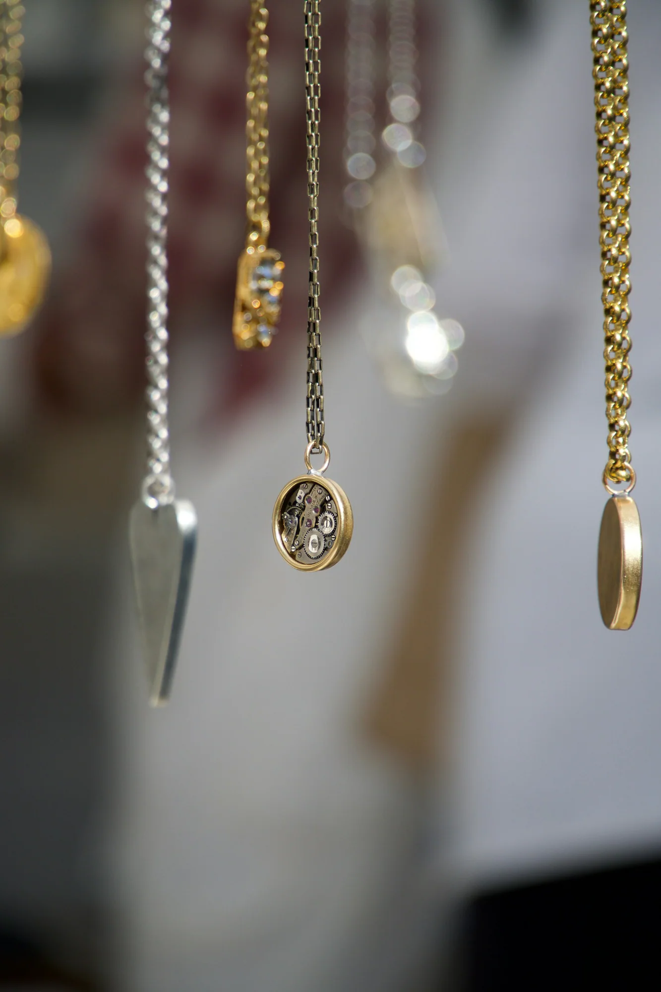 Three delicate gold charm necklaces hanging