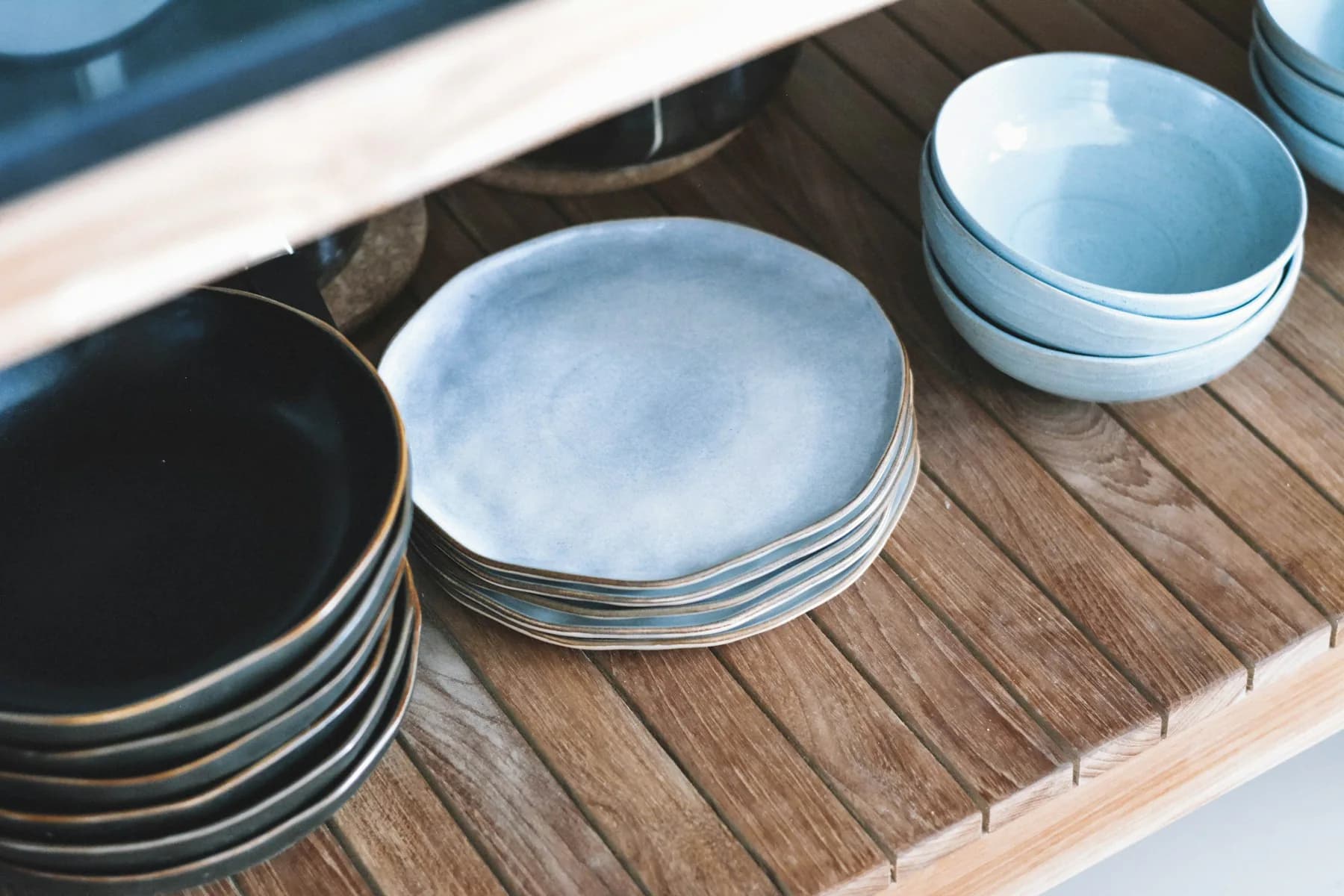 Stack of blue reactive-glaze stoneware plates on a wooden table