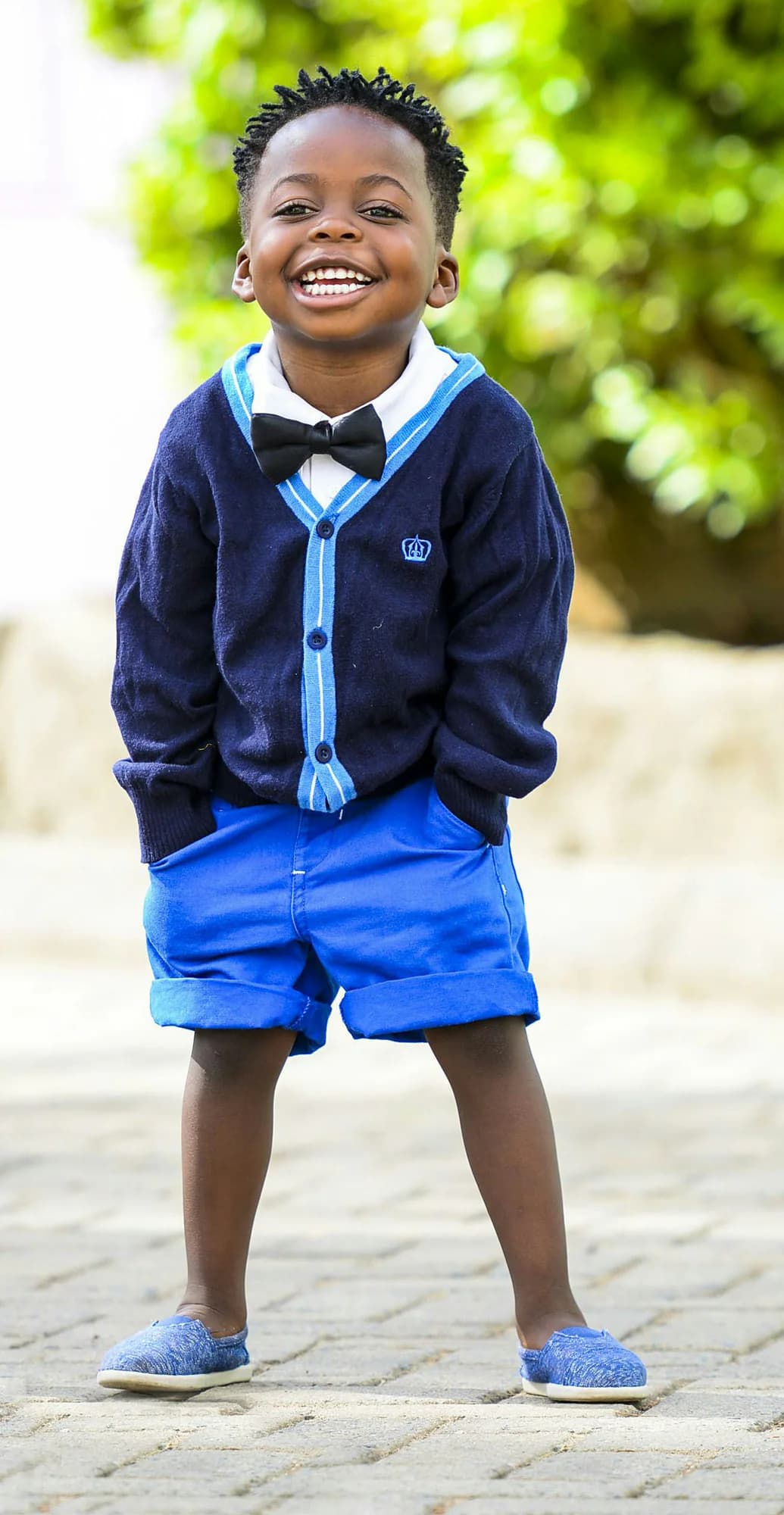 Young boy wearing a navy cardigan and bow tie