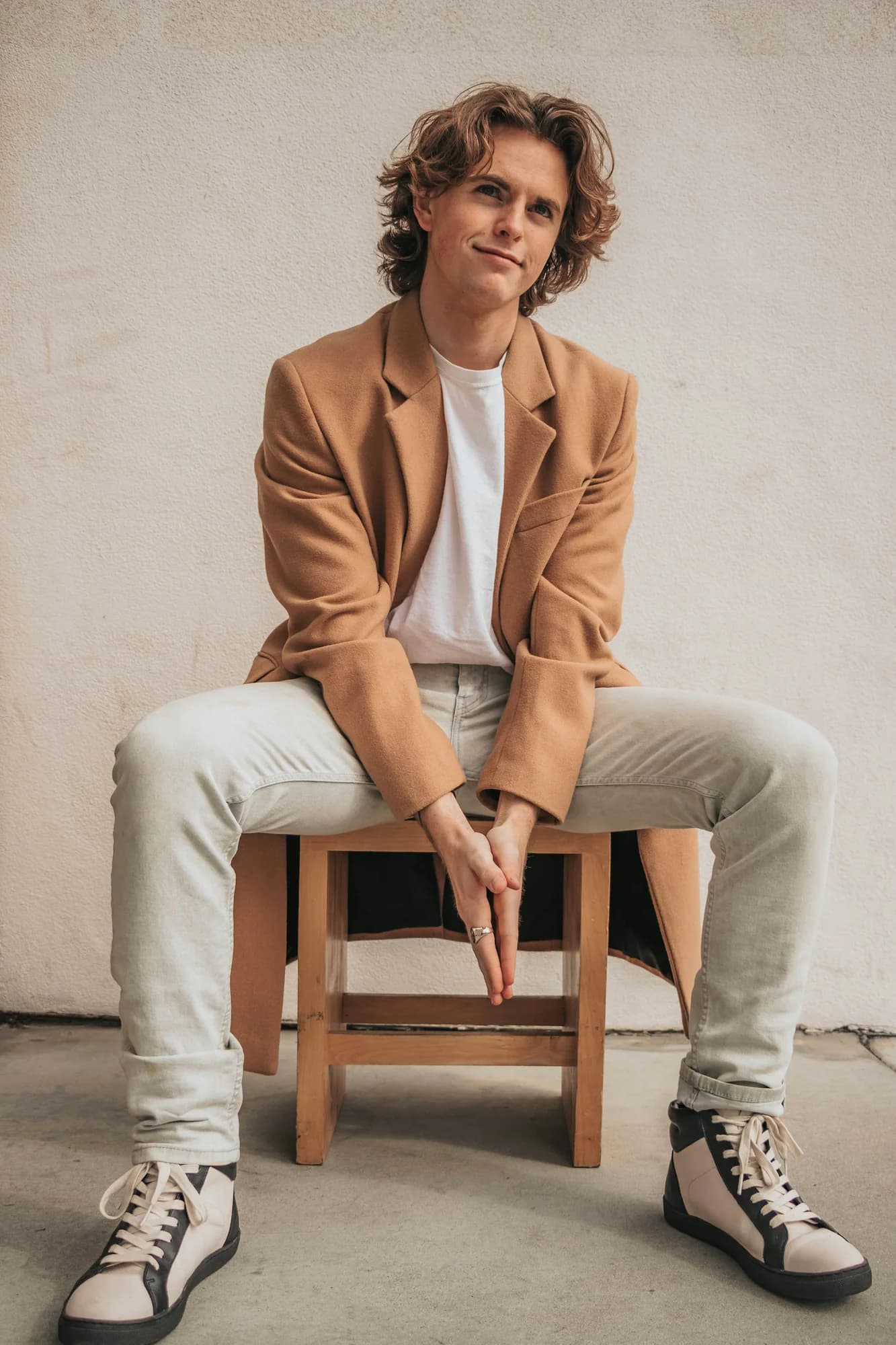Man in a camel blazer sitting on a stool