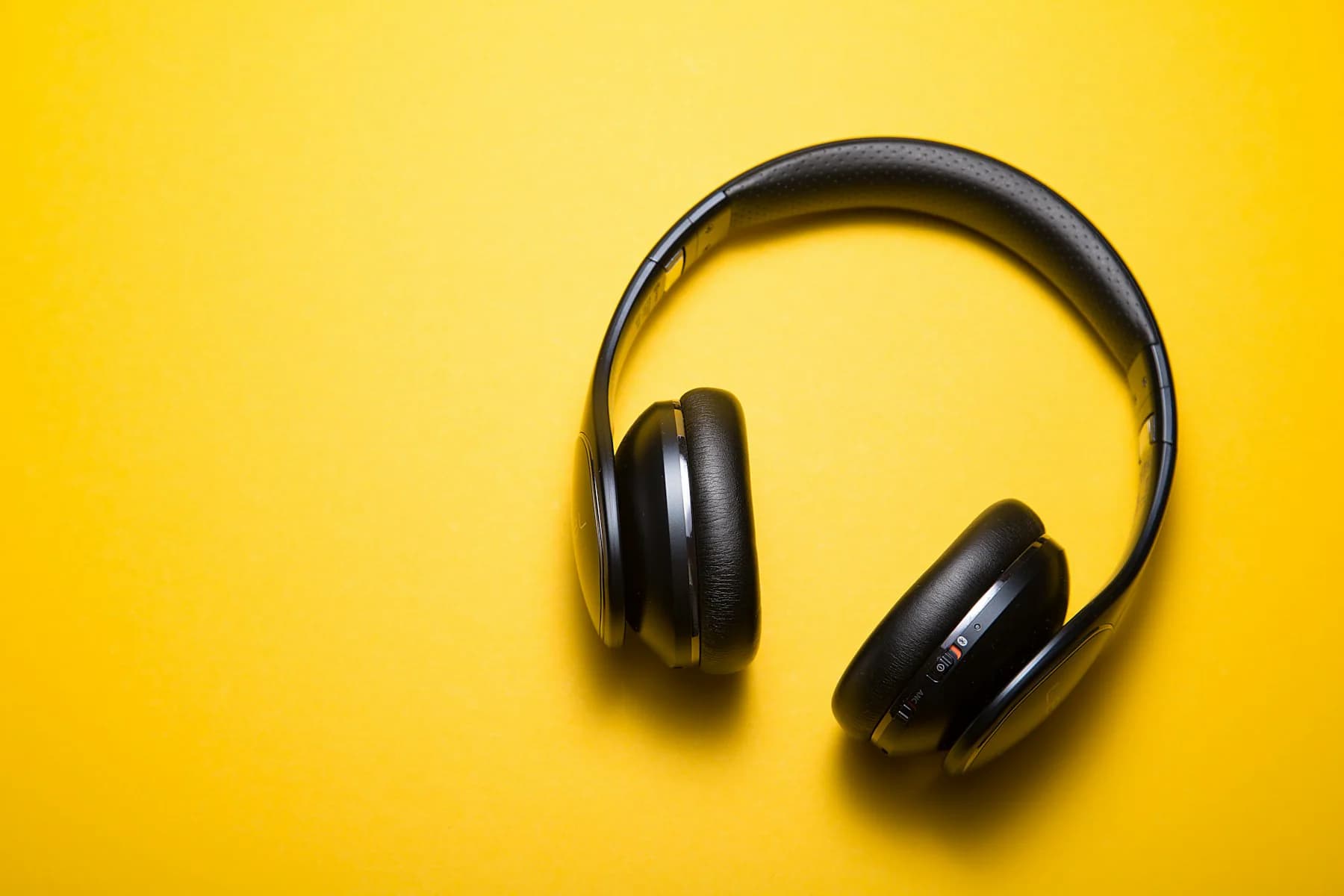 Black wireless headphones on a yellow background