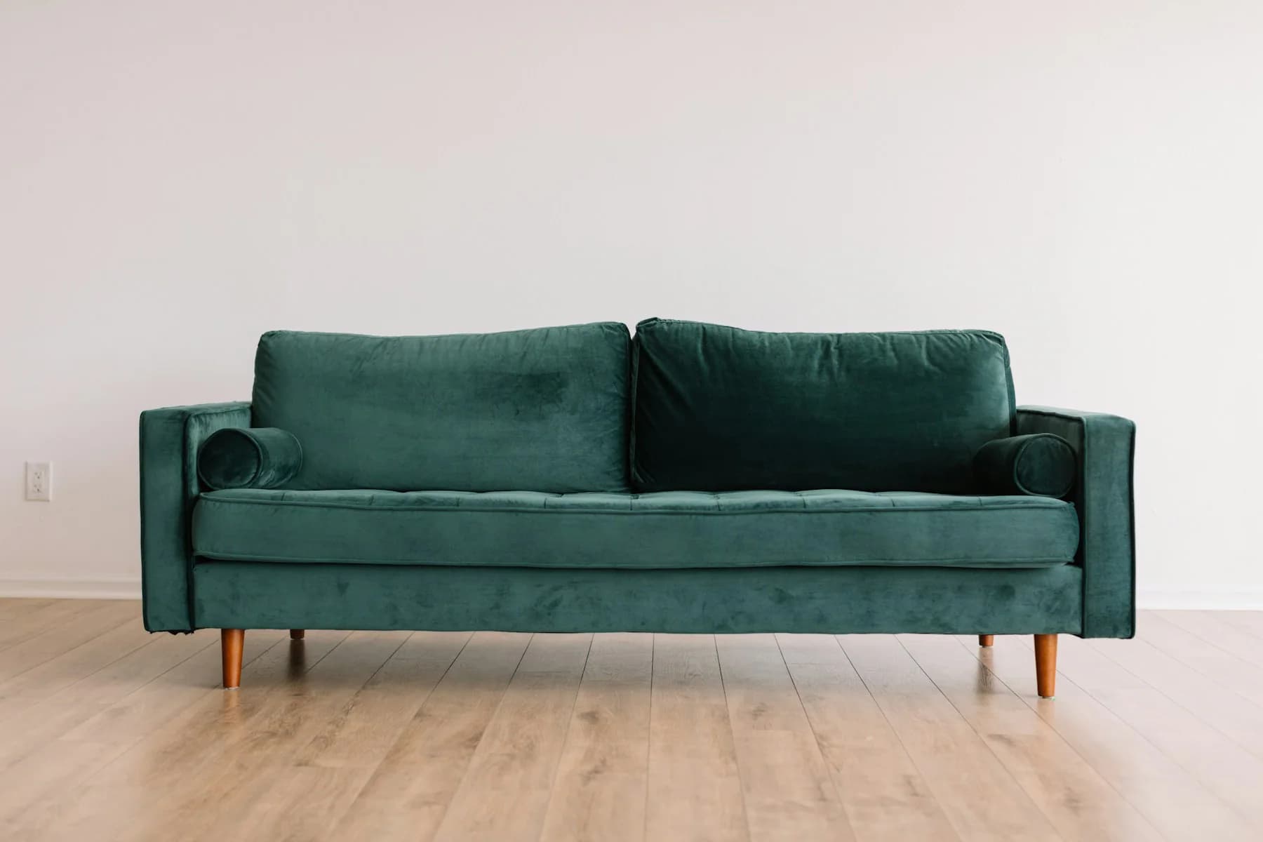 Emerald green velvet sofa in a bright room