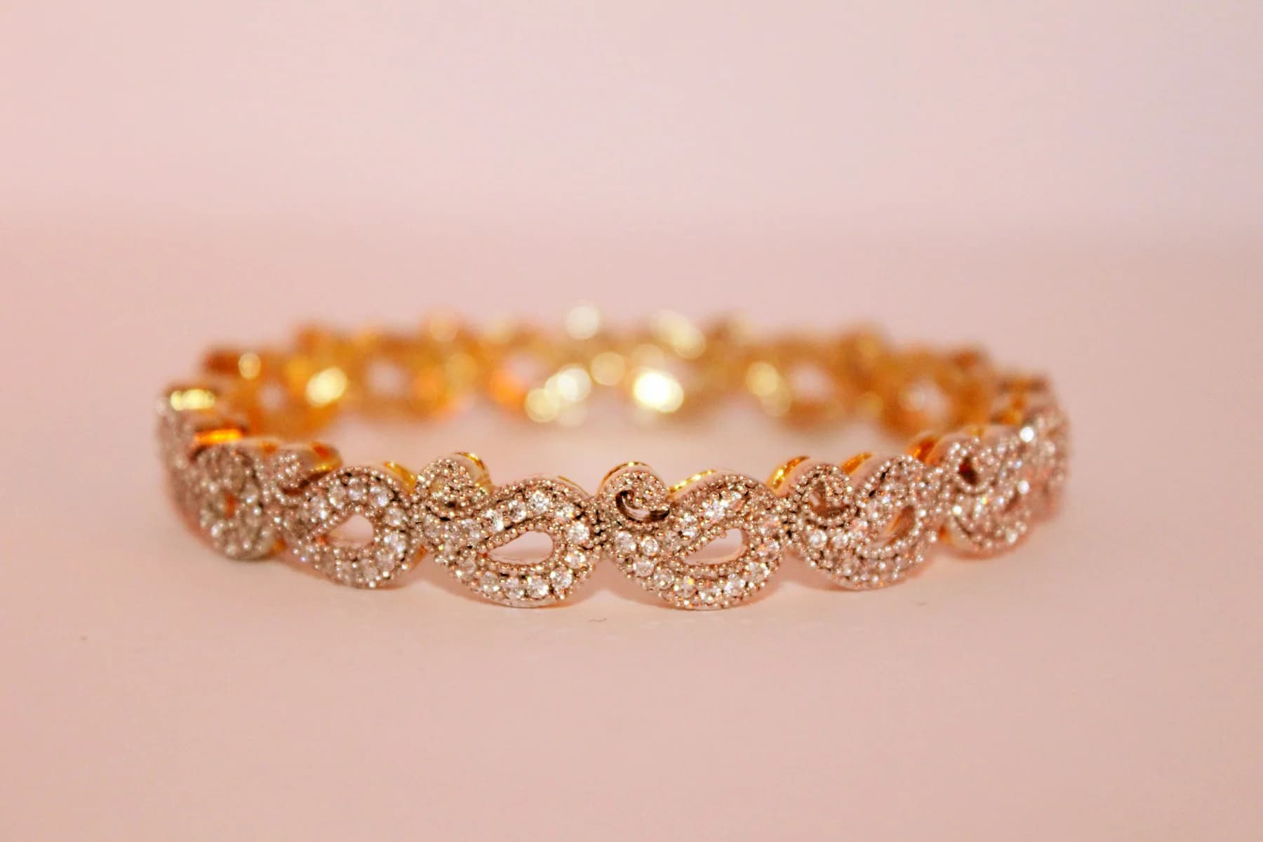 Rose gold pavé bangle on a pink background