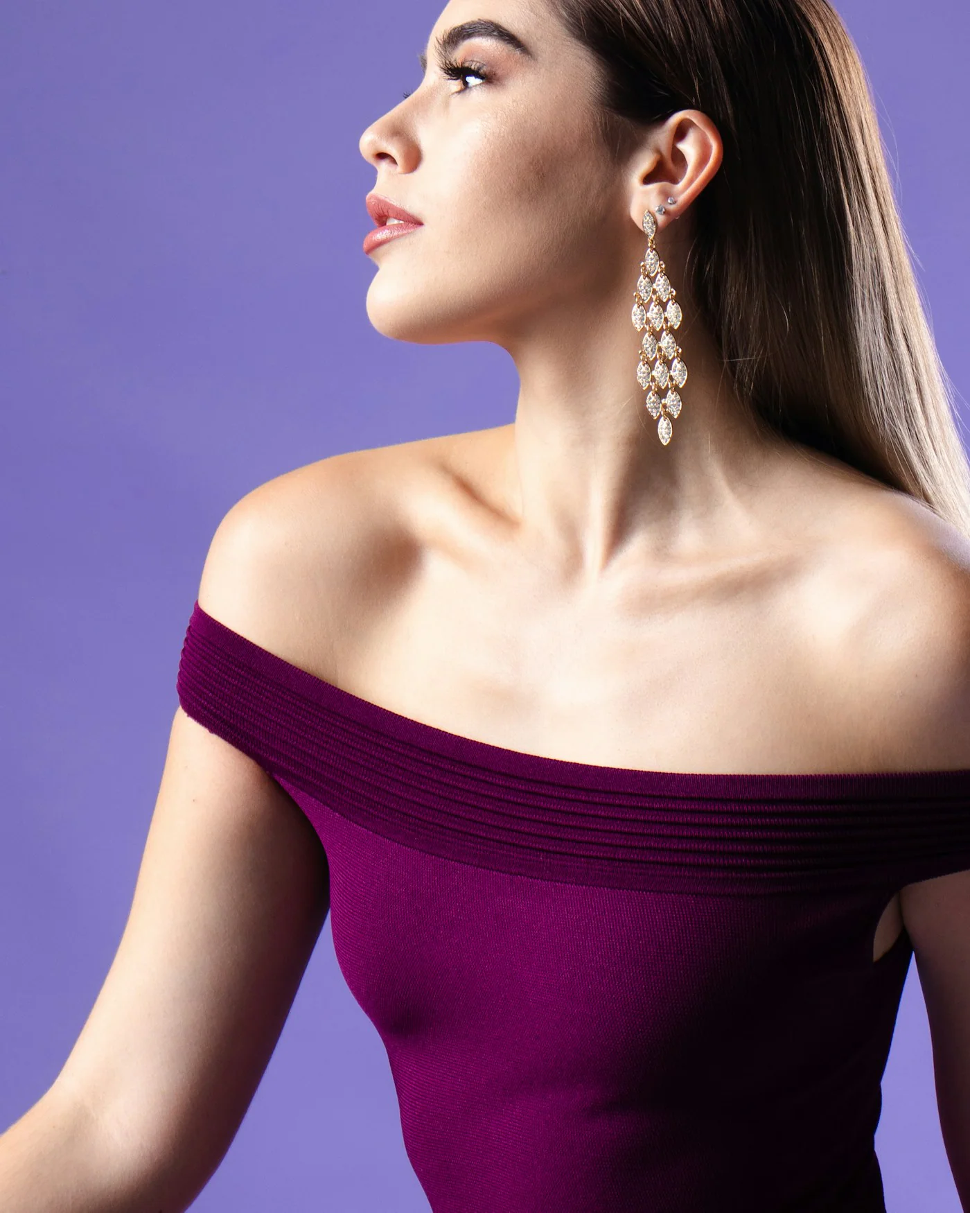 Woman wearing a plum off-the-shoulder top against a violet background — detail