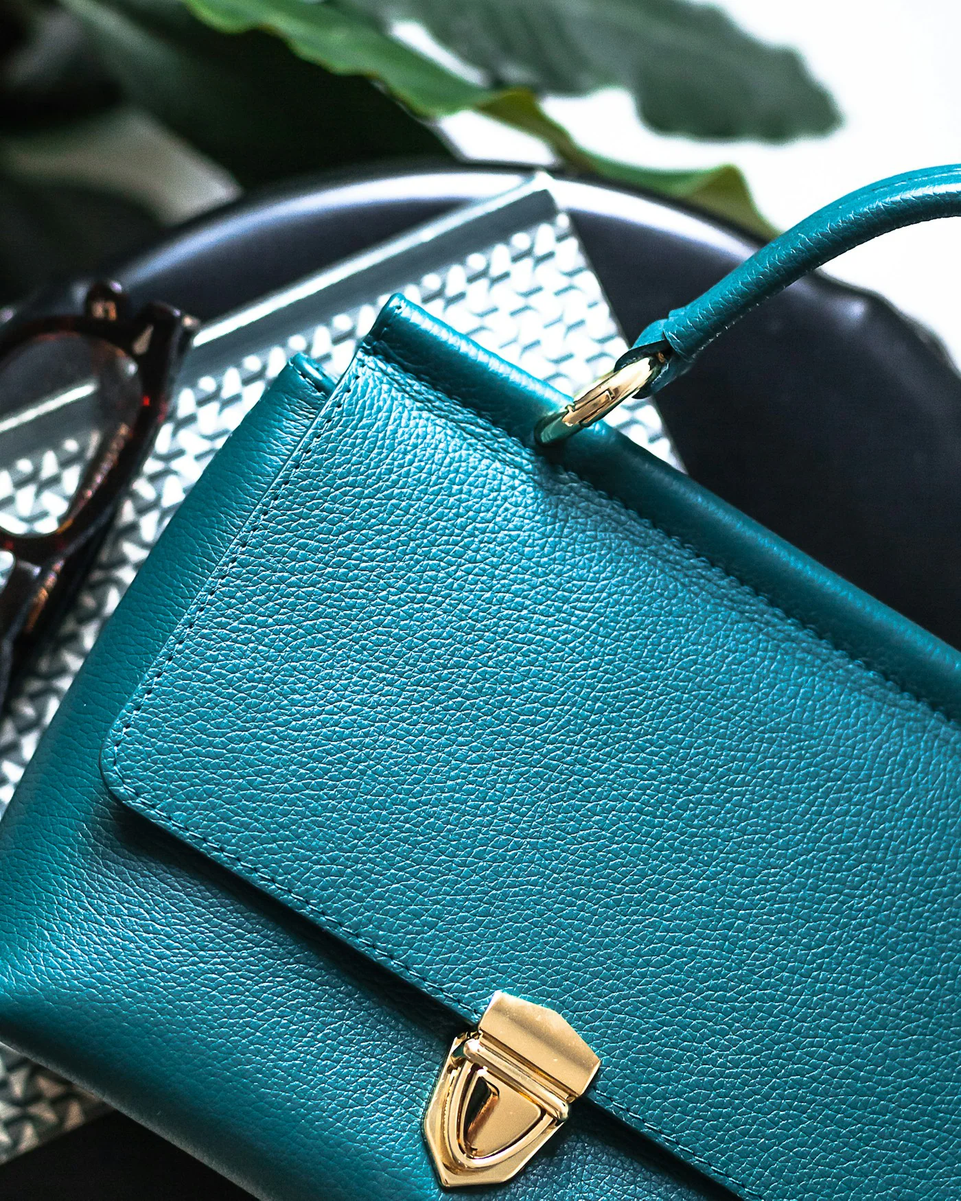 Teal leather satchel bag with a gold push-lock — detail