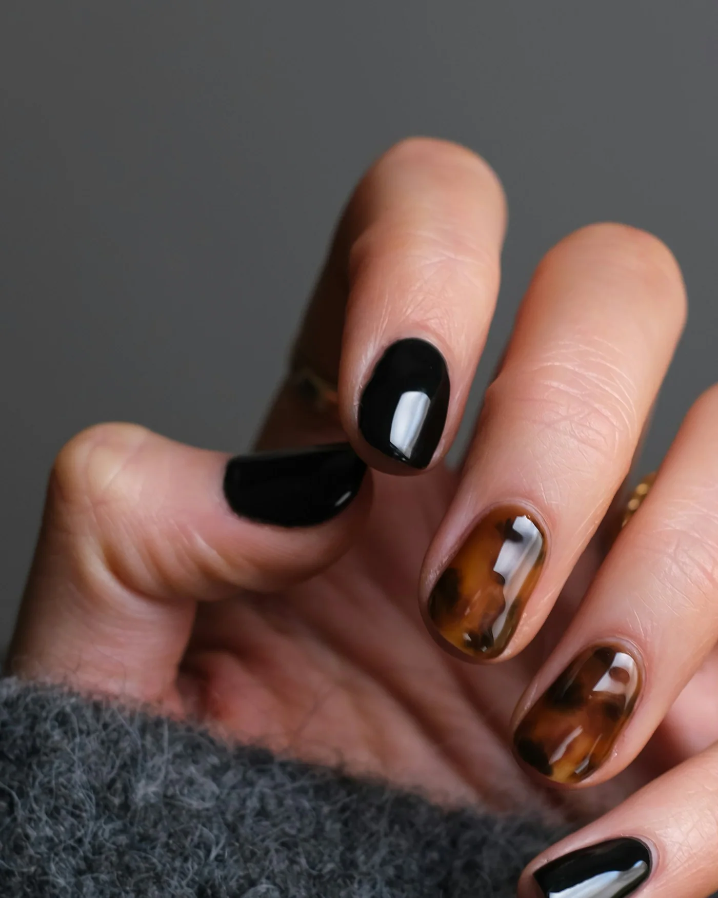 Manicured hands with black and nude nail art — detail
