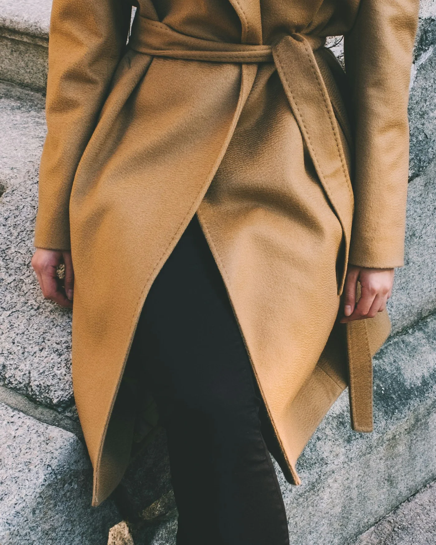 Person wearing a belted camel trench coat — detail