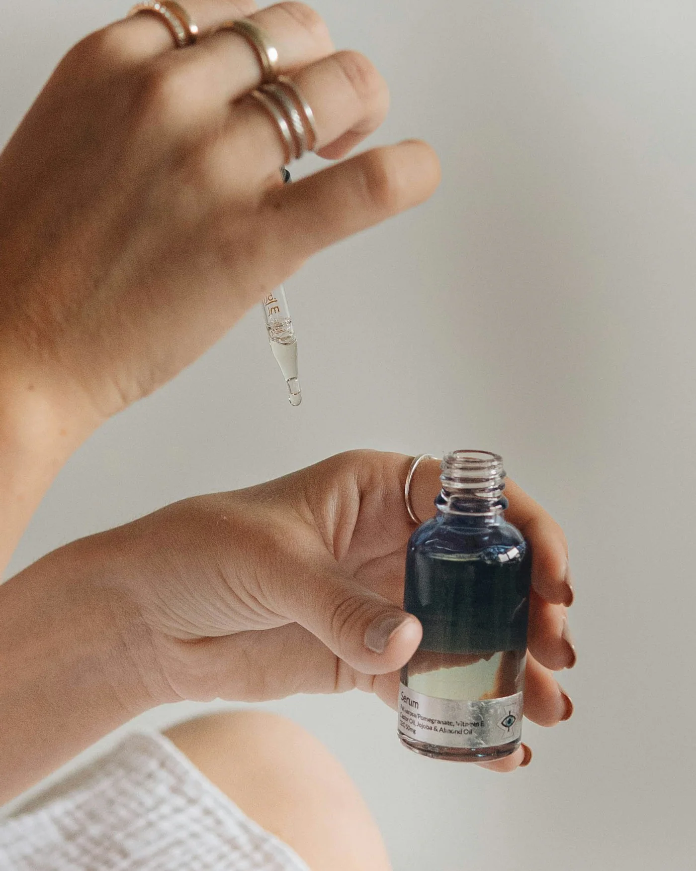 Hand holding a small dark glass serum bottle with a dropper — detail