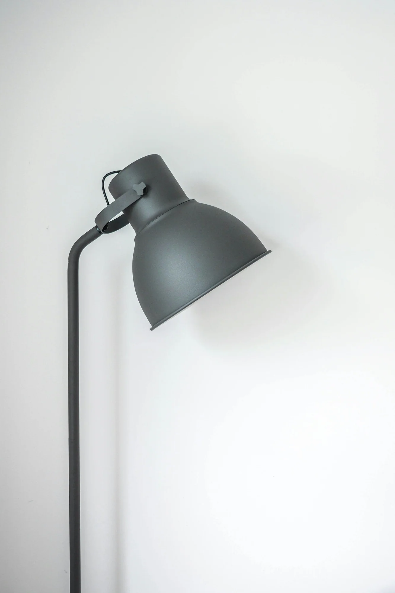 Grey floor lamp against a white wall