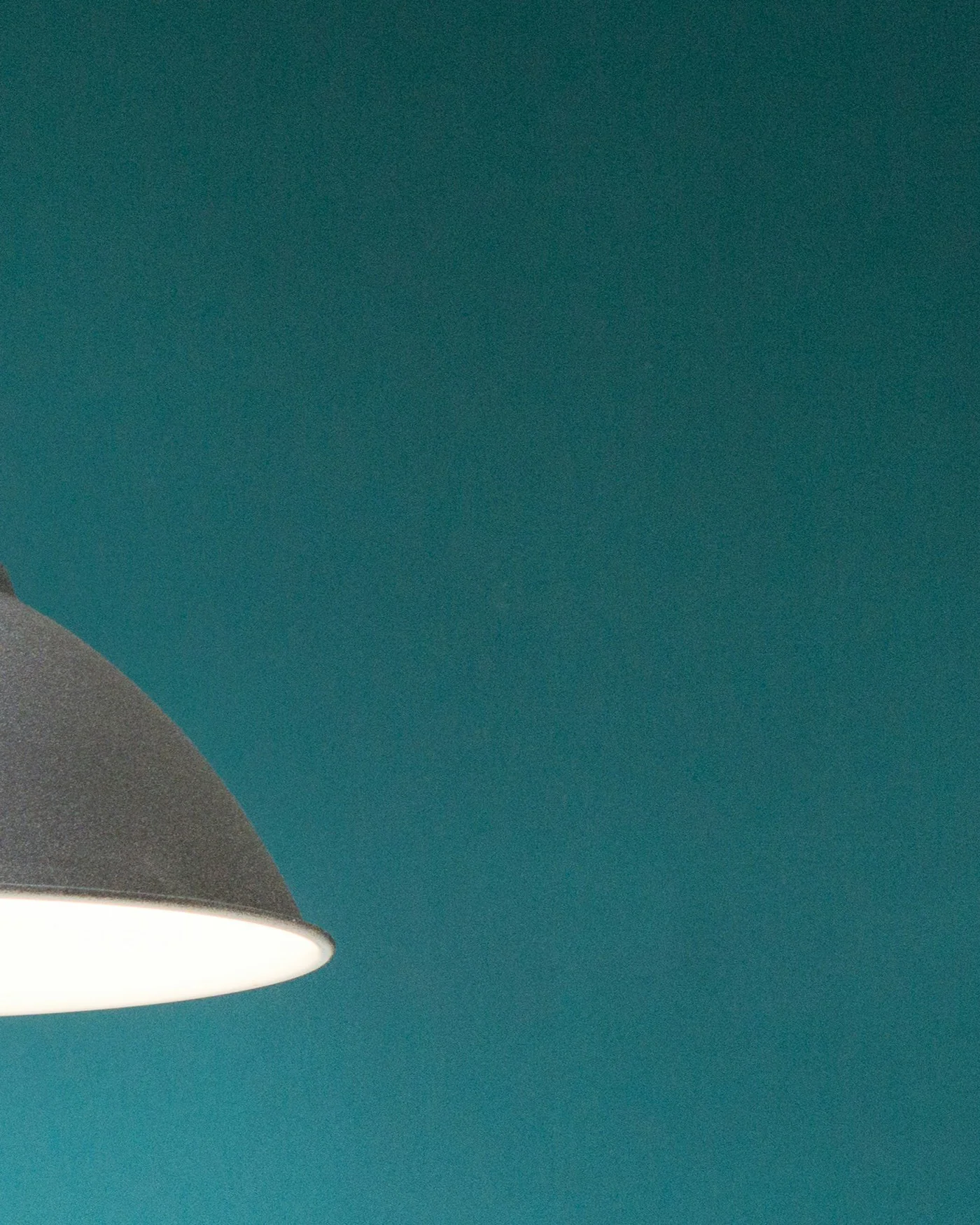 White dome pendant light against a teal wall — detail