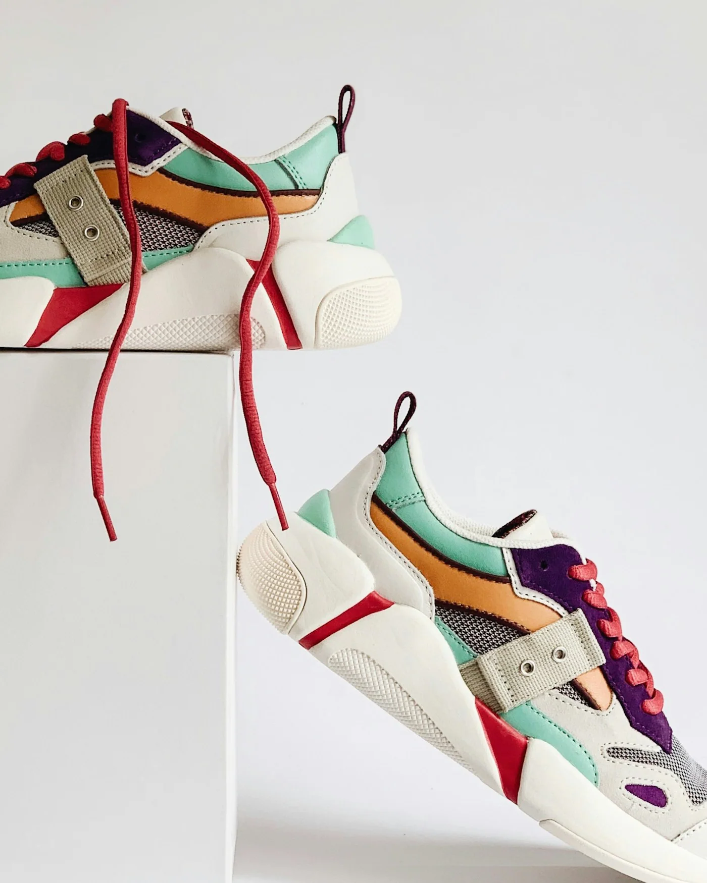 Multi-coloured chunky retro sneakers on white plinths — detail