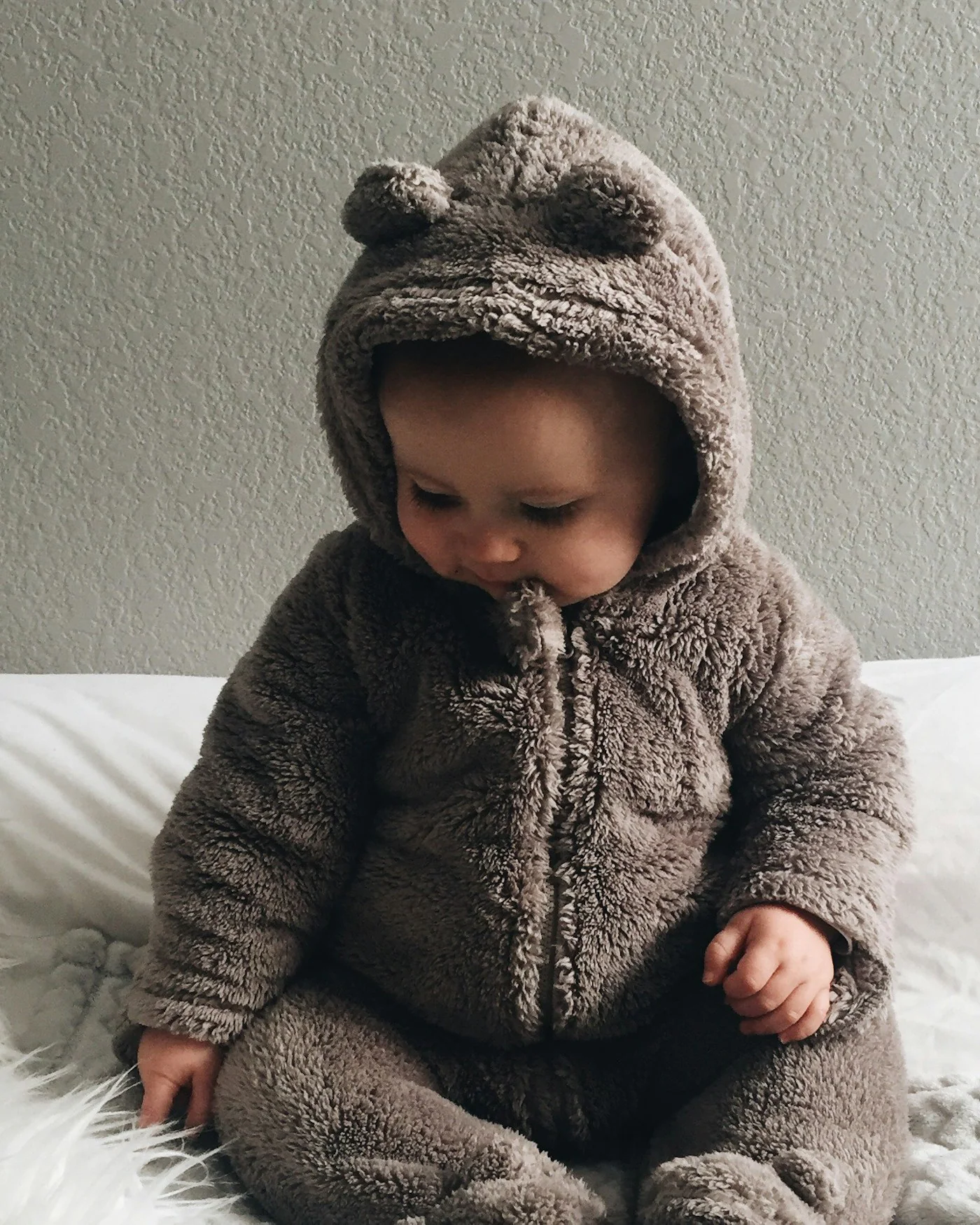 Baby wearing a brown bear-ear fleece onesie — detail